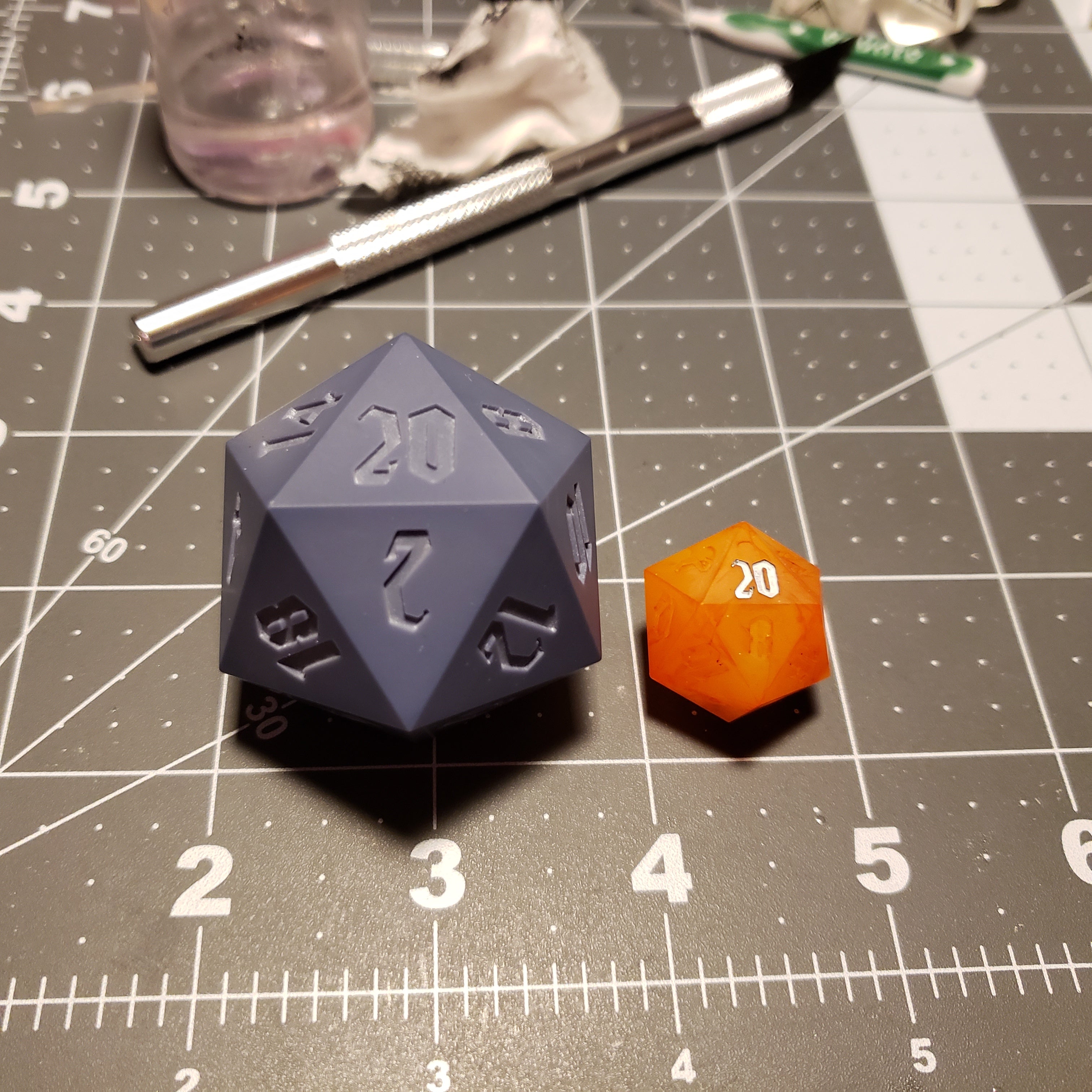 Almost 2 inich wide D20 Dice next to a standard size orange D20
