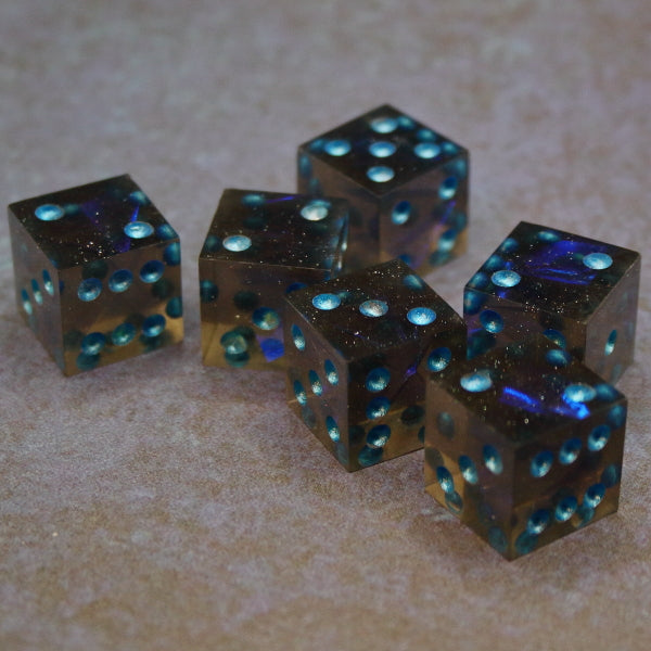 6 piece set of sharp edged Pip D6s that are Dark tinted glittered with blue-ish tinted Mylar inclusions. Inked in a metallic blue.